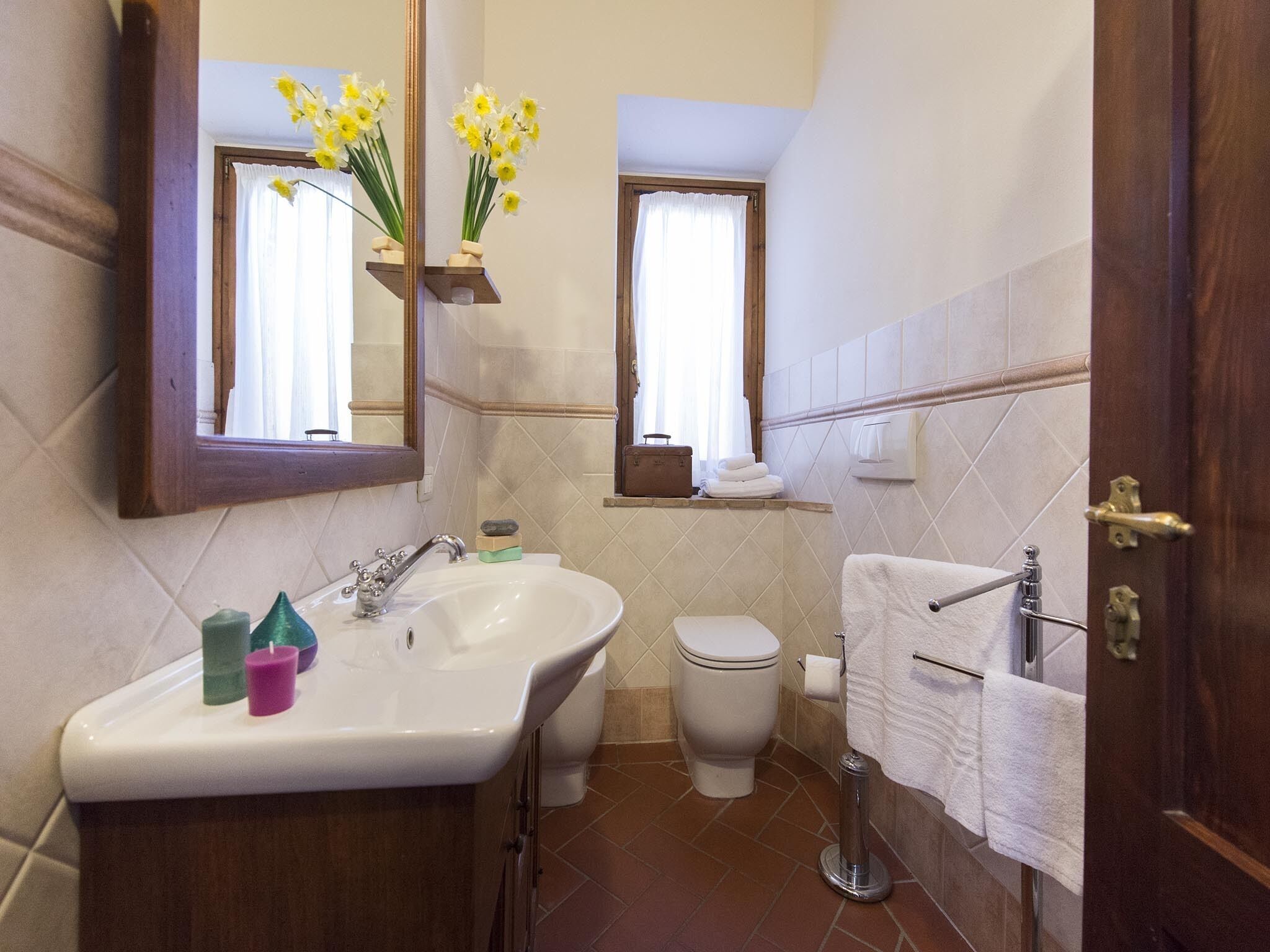 Een badkamer met een wastafel, spiegel, toilet en handdoekhouder.