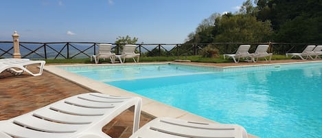 Una piscina al aire libre de temporada, sombrillas, tumbonas