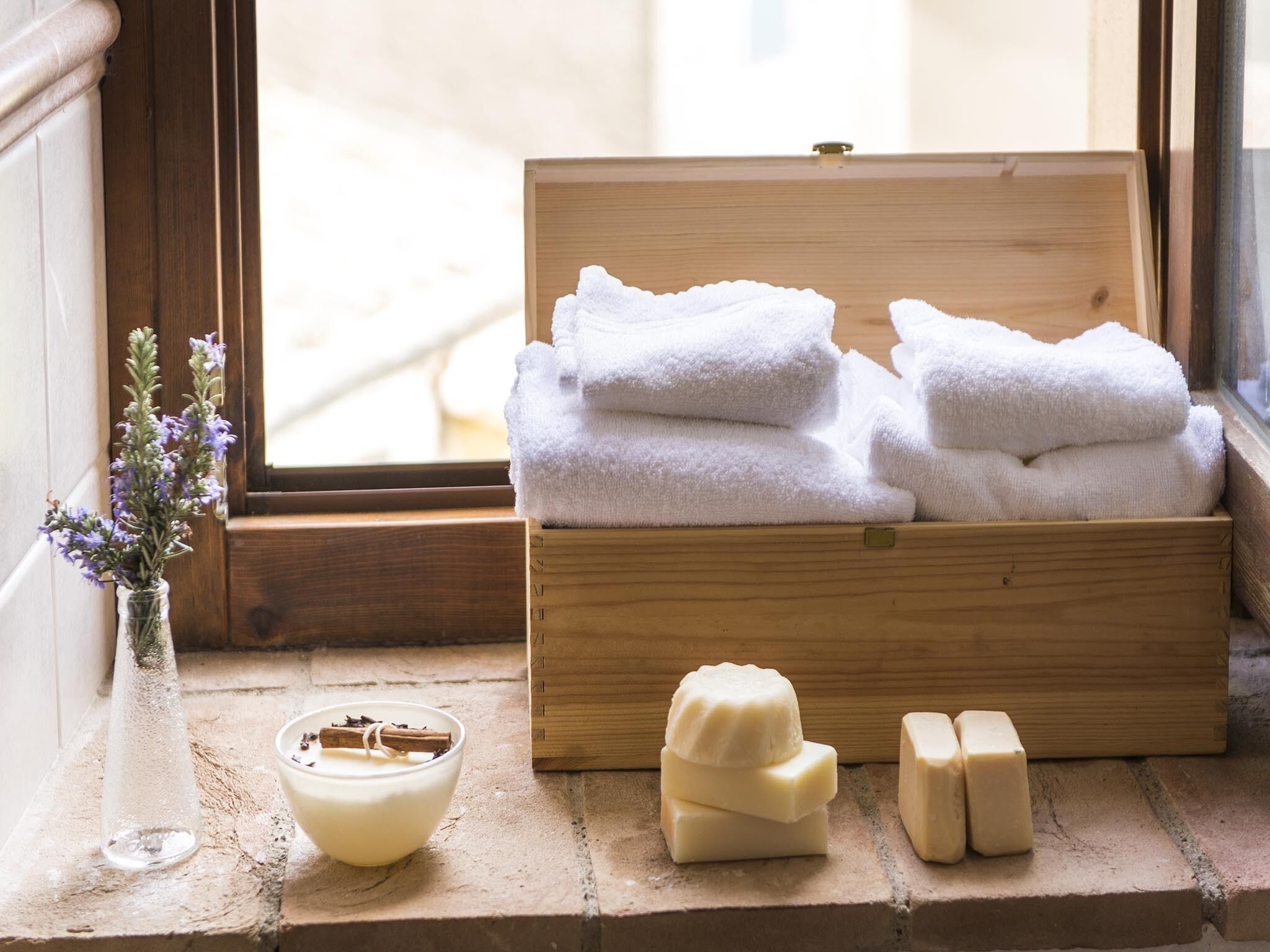 A wooden box with folded towels and soap on a windowsill.