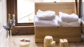 A wooden box with folded towels and soap on a windowsill.