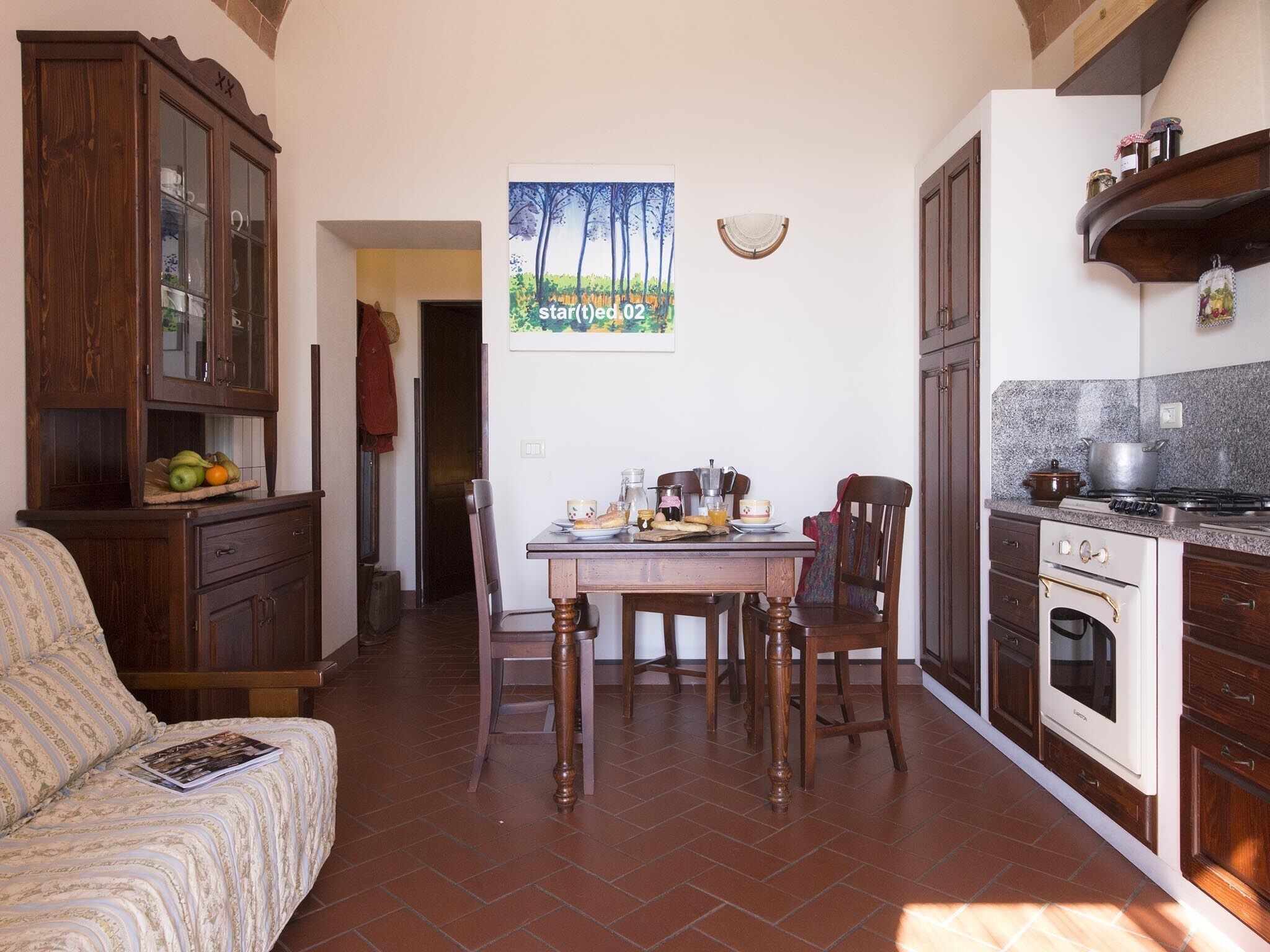 A cozy kitchen with wooden cabinets, a dining table with chairs, and a kitchen island.