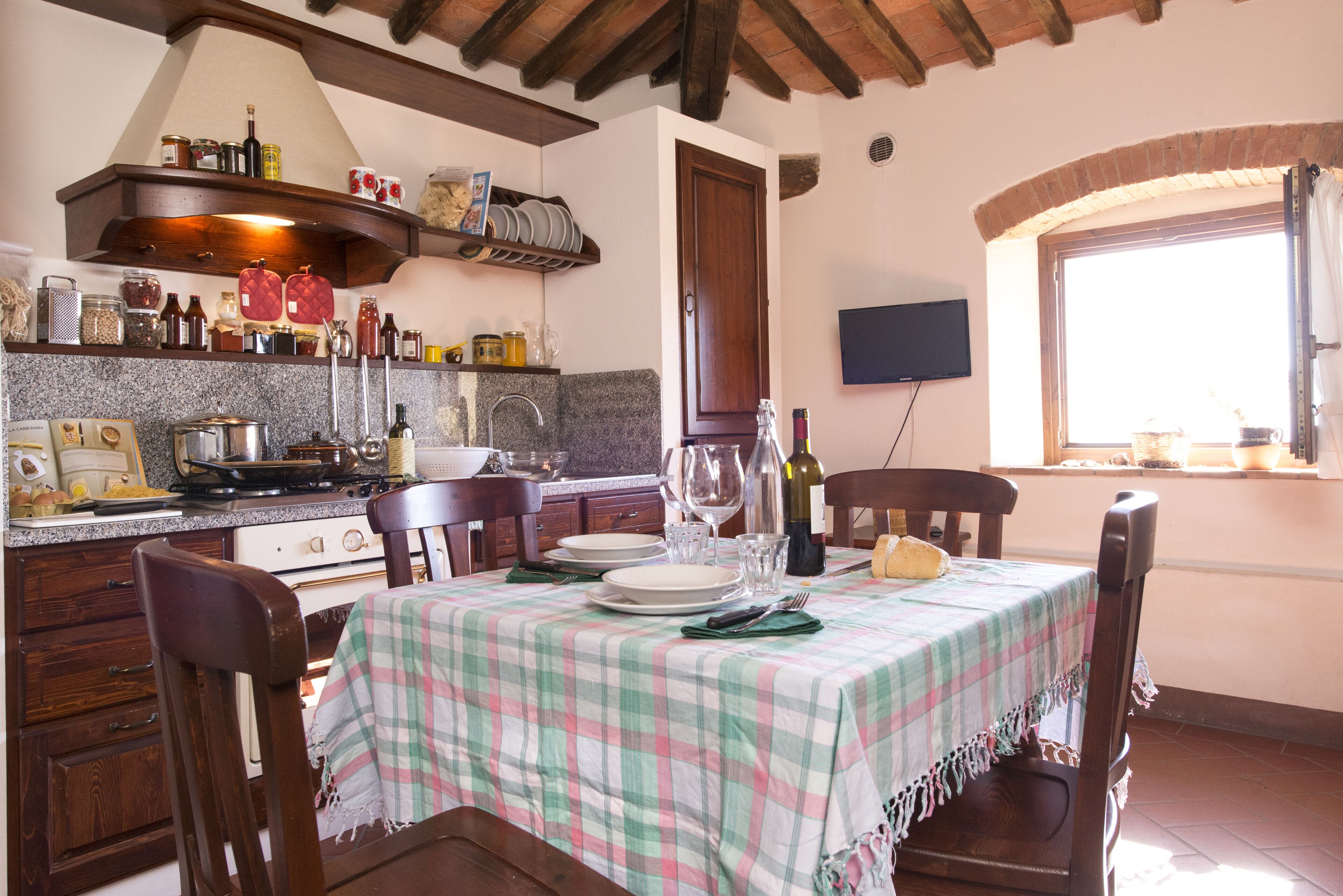 Una cocina con armarios de madera, una estufa y una mesa de comedor con platos y vasos.