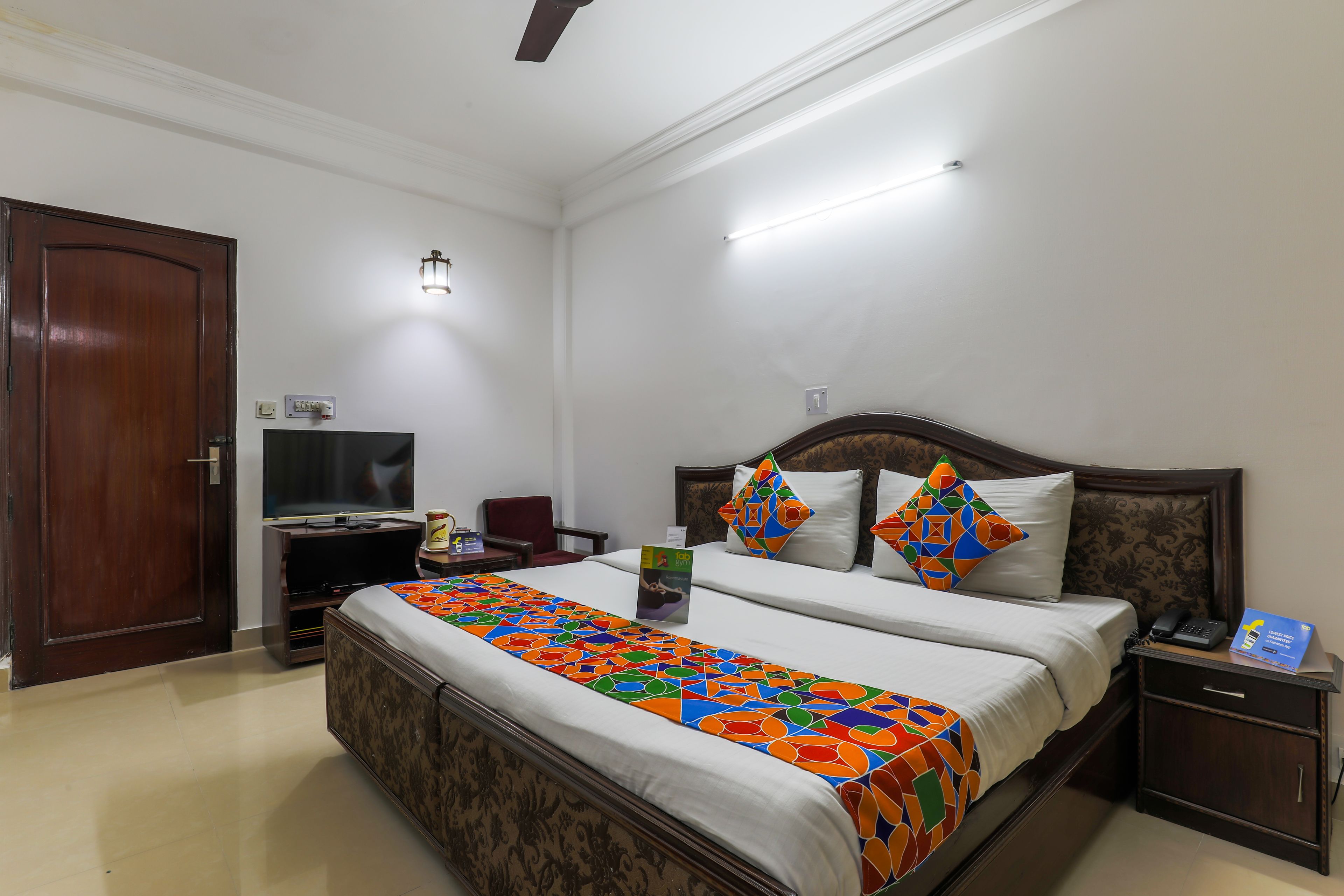 A hotel room with a large bed, a TV, a desk, and a chair.