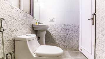 Une salle de bain avec des toilettes, un lavabo et une douche.