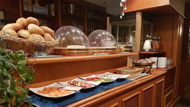 Montaje de bufé con diversas opciones de comida, una cesta de pan y un mantel individual azul.