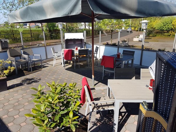 An outdoor patio with tables and chairs, a pool, and a covered seating area. - Das Möwenstübchen (Wurster Nordseeküste)