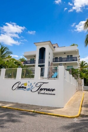 A white building with balconies and a sign that reads 'Ocean Terrace Condominium.'