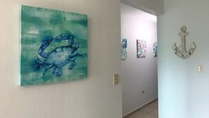 A hallway with a blue abstract painting and a wall-mounted anchor decoration. - Beautiful Beach Apartment at Sandy Beach, Rincon (Rincon)