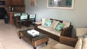 A living room with a sofa, coffee table, and chairs. There is a kitchen area with cabinets and a microwave. - Beautiful Beach Apartment at Sandy Beach, Rincon (Rincon)