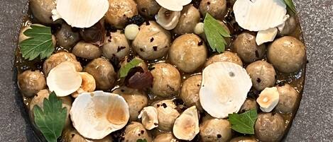 Un plato hondo con elementos redondos y marrones, posiblemente comida, decorado con hojas verdes y rodajas blancas.