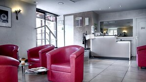 Een moderne receptie met rode leren fauteuils, een receptiebalie en een goed zichtbaar menubord.