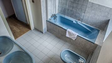 Un baño con bañera, dos lavabos y suelo de baldosas.