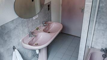 Un baño con un lavamanos rosa, un bidé, una bañera y un espejo con apliques de pared.
