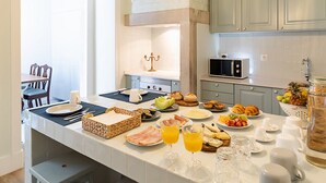 Una cocina moderna con una isla grande, armarios de colores claros e iluminación colgante.