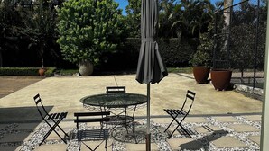 Un patio al aire libre con una mesa redonda y sillas, rodeado por un sendero de grava.