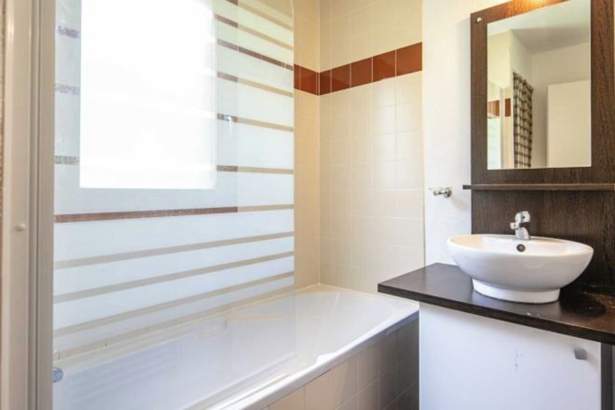 Un baño moderno con bañera, lavamanos y espejo.