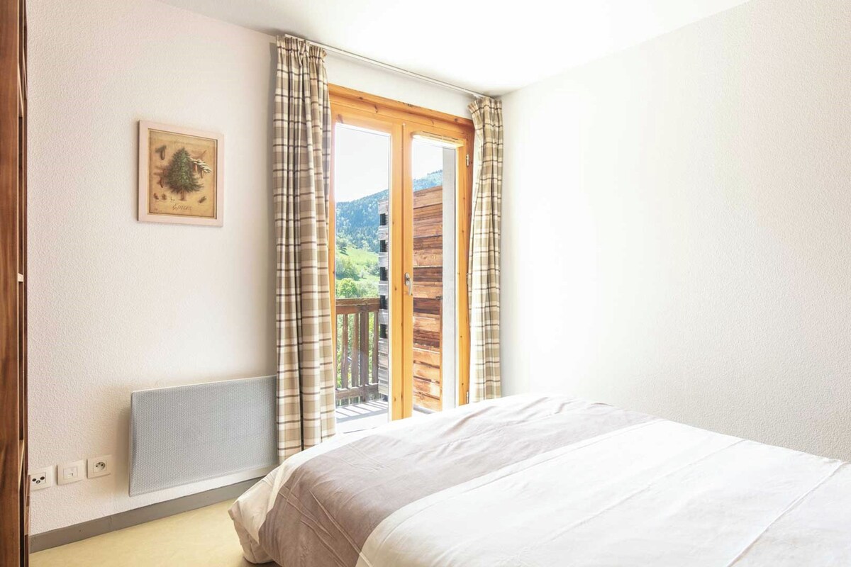 Une chambre à coucher avec un lit, une fenêtre avec des rideaux, un radiateur et un tableau accroché au mur.