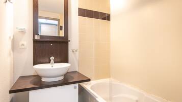 A bathroom with a white sink, a mirror, and a bathtub.