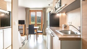 Una cocina compacta con comedor, televisor y vistas al exterior.