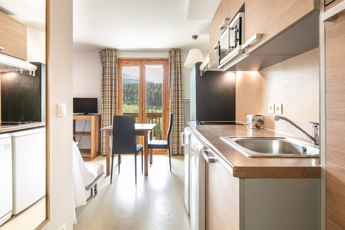 A compact kitchen with a dining area, a television, and a view of the outdoors.