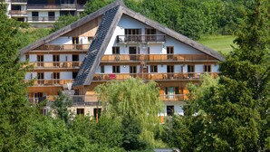 Un hotel de varios pisos con balcones, rodeado de árboles.