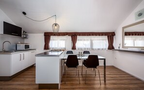 A modern kitchen with a central island, white cabinets, a microwave, and a hanging light fixture.