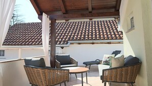 Eine Terrass mit Korbmöbeln, einem Ziegeldach und einer weißen Wand.