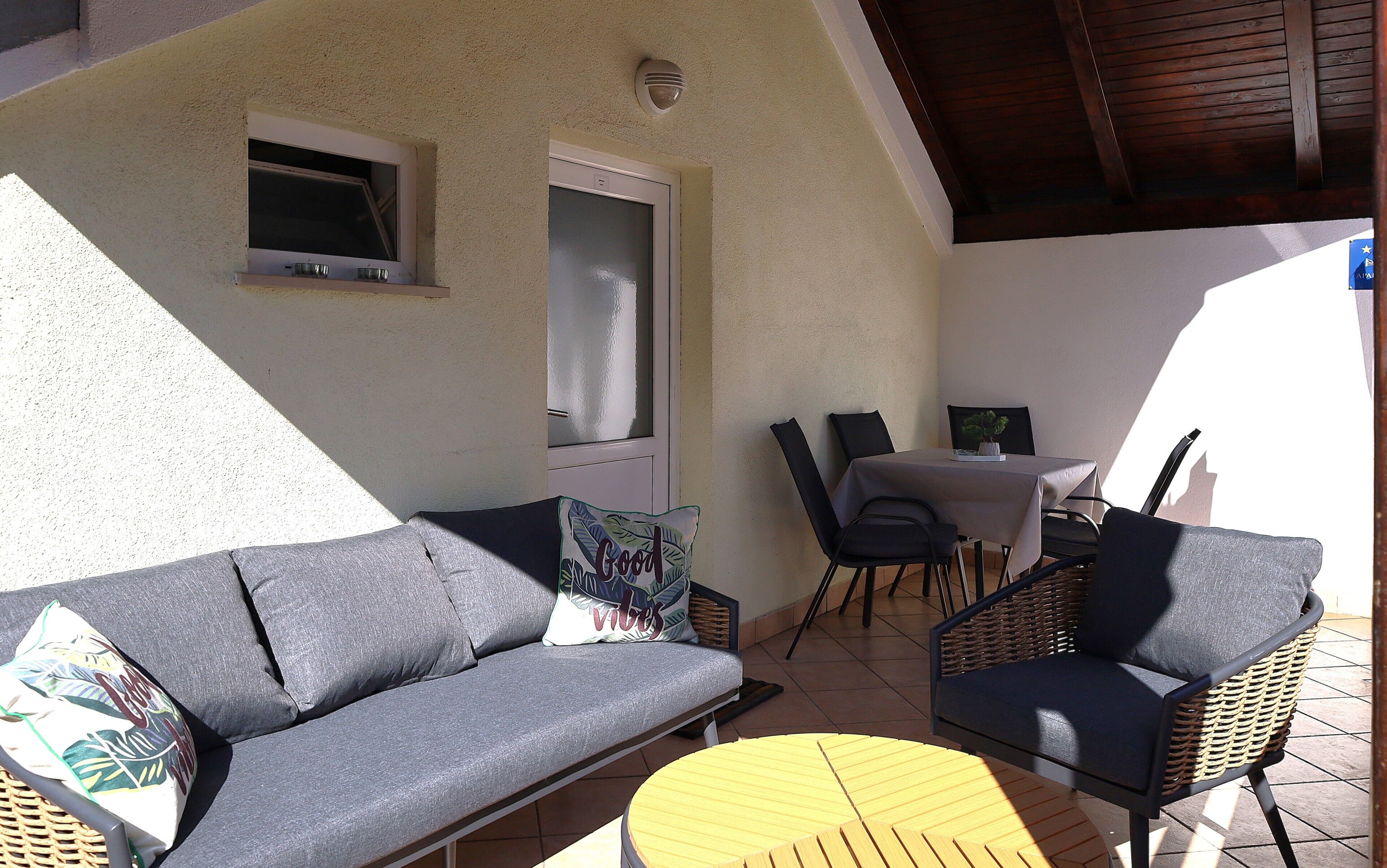 Une terrasse avec un canapé, des chaises, une table et une petite table ronde.