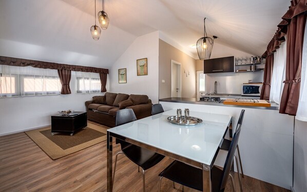 A modern kitchen with a dining area, a sofa, and a TV.