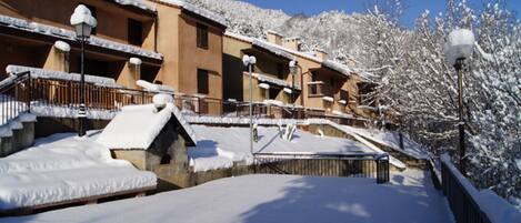 A snow-covered building with multiple balconies and a staircase leading to the entrance.