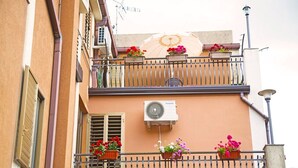A building with a balcony, air conditioning unit, and flower planters. - Pergusa Lake Home (Enna)
