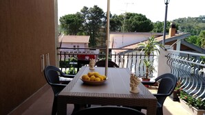 A balcony with a table, chairs, a bowl of lemons, a bust sculpture, and potted plants. - Pergusa Lake Home (Enna)