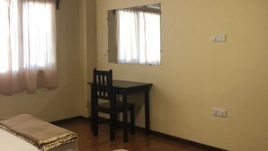 Habitación de hotel con dos camas, un escritorio y una silla.