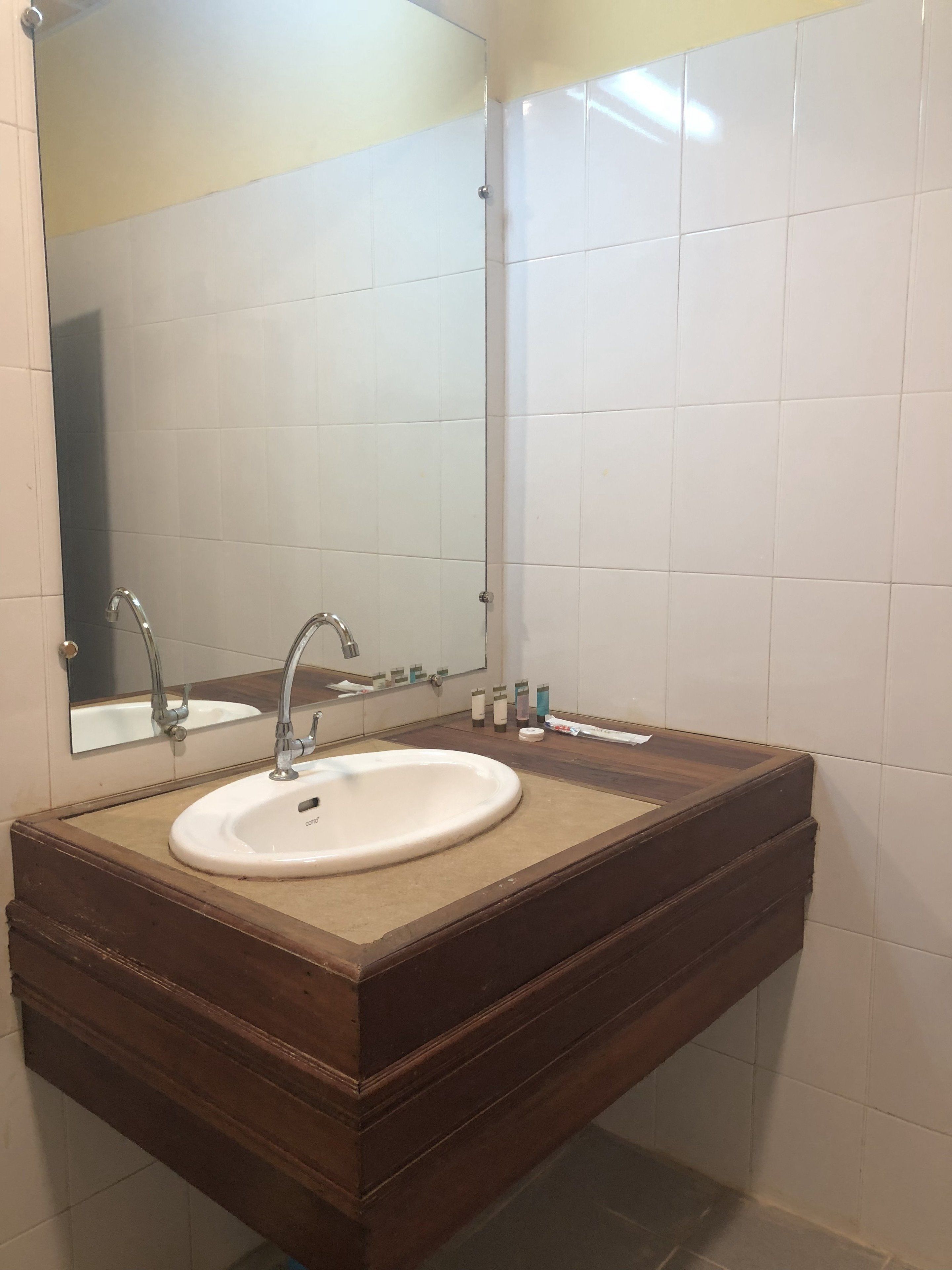A bathroom with a wooden vanity, a white sink, and a mirror above it.