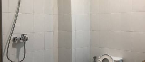 Un baño pequeño con un inodoro, ducha y un cubo de basura.