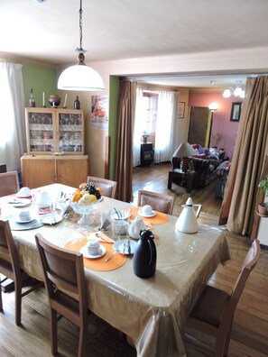 A dining area with a table set for four, surrounded by wooden chairs. A cabinet with glass doors is visible in the background. - Hospedaje La Nuit (Cusco)