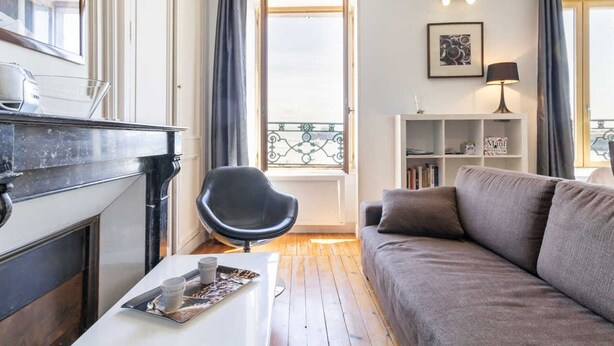 A living room with a fireplace, a black chair, a grey sofa, a white coffee table, and a bookshelf.