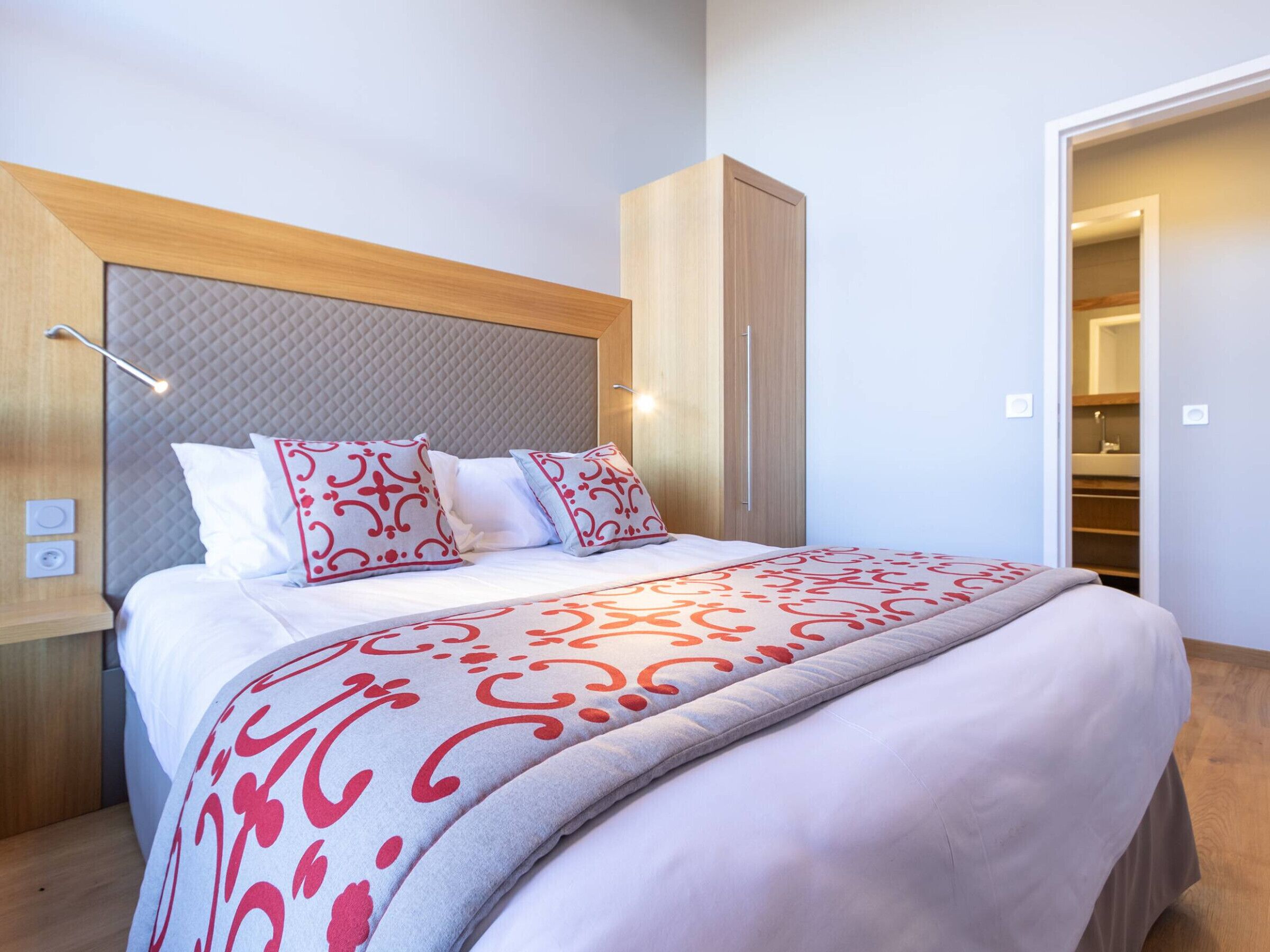 Un dormitorio moderno con una cama grande, cabecera con diseño acolchado y un armario de madera.