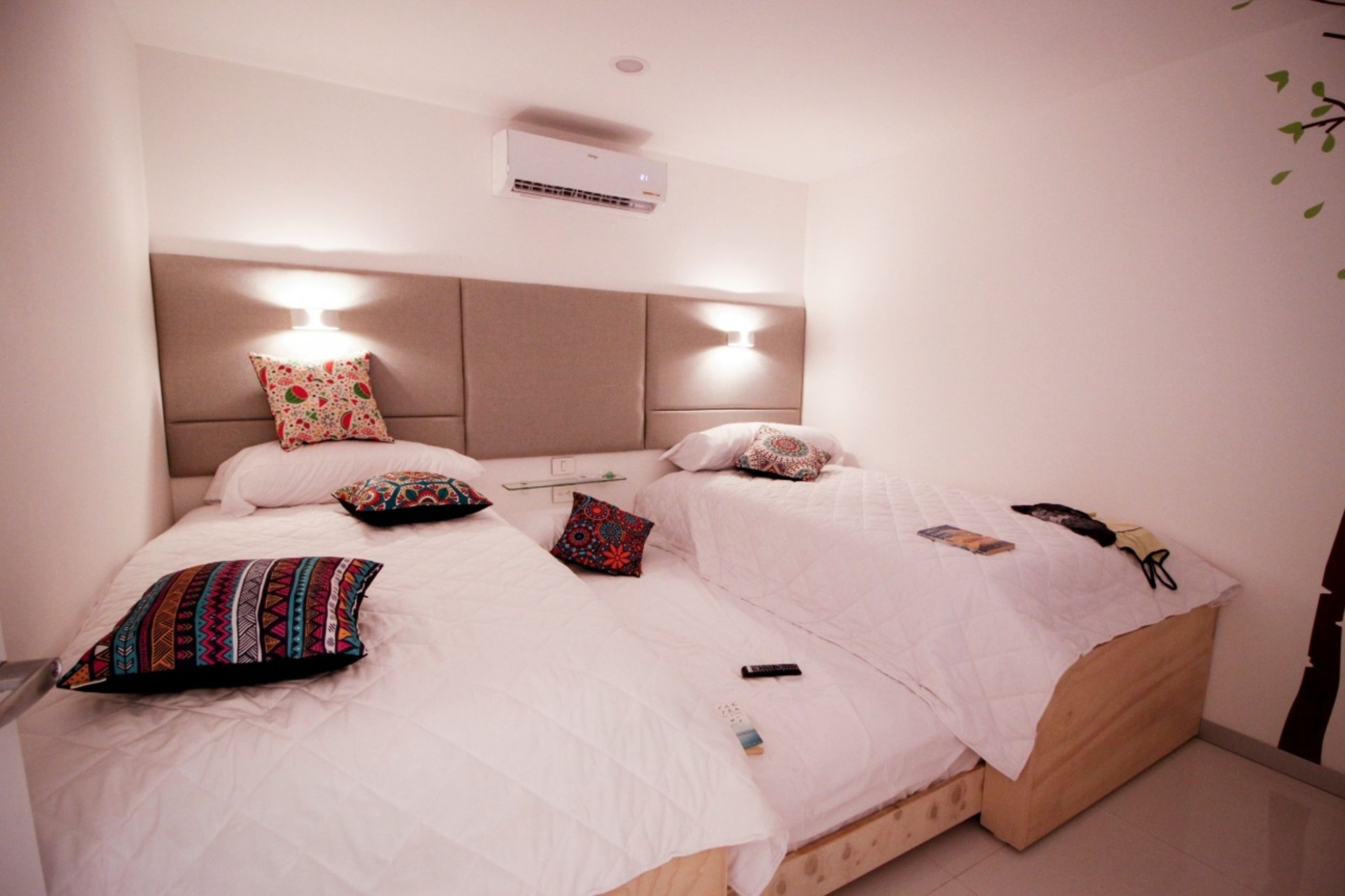 Una cama doble con dos almohadas, una mesita de noche y un aire acondicionado instalado en la pared.