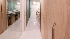 Ein moderner Hotelkorridor mit langer Diele, spiegelnden Schrankschrännen und einer Reihe von Waschbecken.