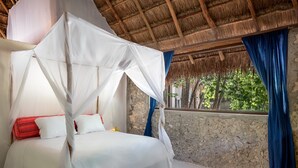 A room with a bed under a canopy, a stone wall, and a window with blue curtains. - Seclusive & Relaxing villa in the jungle of Xpu-Ha by Happy Address (Kantenah)