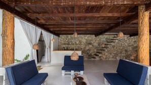 A rustic interior with wooden beams, stone walls, and blue cushioned seating. - Seclusive & Relaxing villa in the jungle of Xpu-Ha by Happy Address (Kantenah)