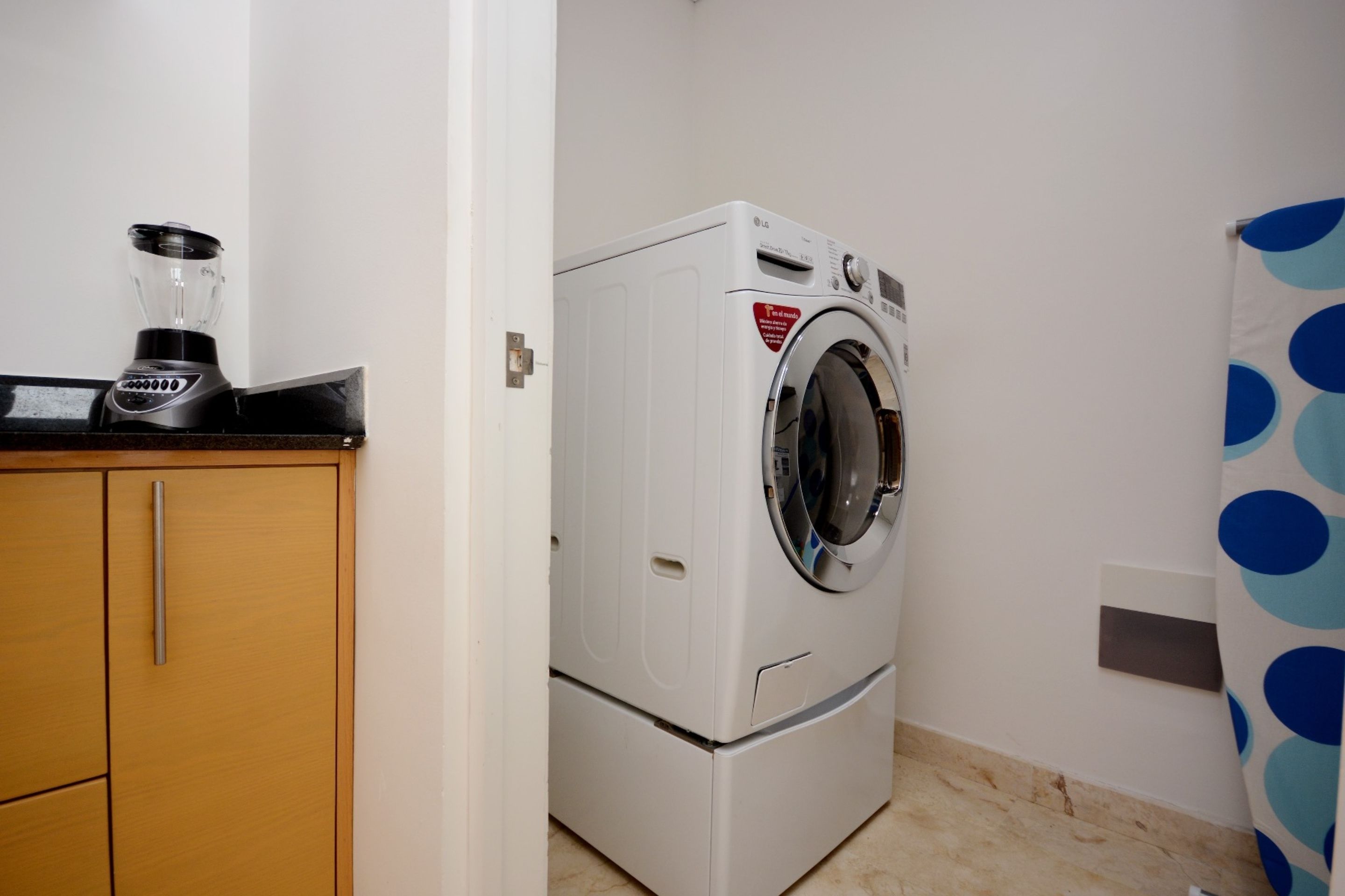 A compact laundry area with a washing machine and a built-in blender.