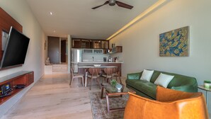 Ein modernes Wohnzimmer mit einem grünen Sofa, einem Couchtisch und einem flachbildfernseher an der Wand.