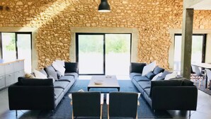 A modern living room with stone walls, two sofas, a coffee table, and a dining area.