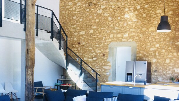 A modern living area with blue sofas, a wooden coffee table, and a stone wall.