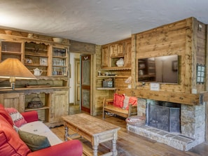 A rustic interior with wooden walls, a fireplace, a television, and a cozy seating area.