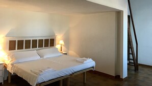 A neatly made bed in a room with a high ceiling and a wooden ladder. - Hotel Su Meriagu (Quartu Sant'Elena)