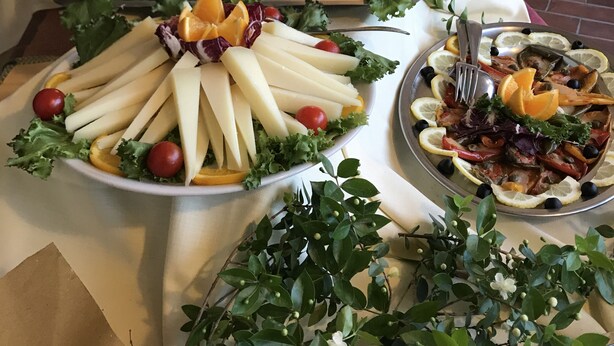 A buffet table with various dishes, including cheese, meats, and salads, arranged on white tablecloths. - Hotel Su Meriagu (Quartu Sant'Elena)