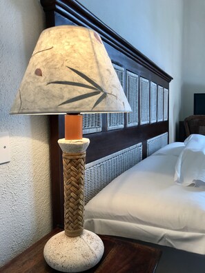 A lamp with a textured shade and a woven base on a wooden nightstand. - Hotel Su Meriagu (Quartu Sant'Elena)